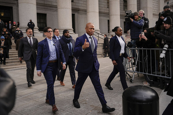 New York Mayor Eric Adams, in a dark suit, strides away from a courthouse's steps. 